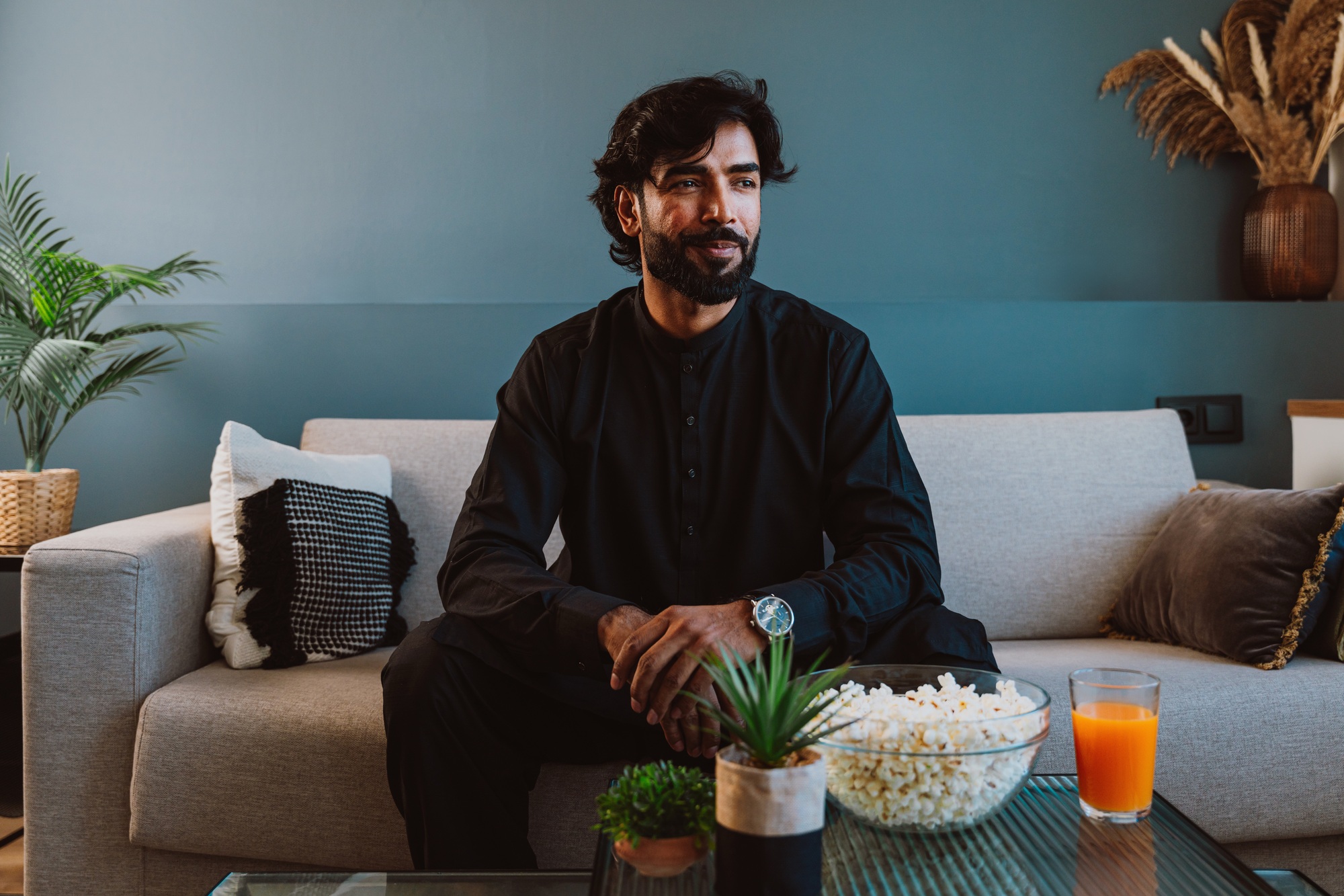 Pakistani guy with traditional outfit eating popcorn.